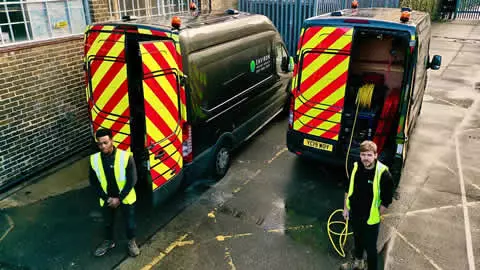 Emergency drainage service team with vehicles displaying reflective safety markings, equipped for stadium and event space drainage management.