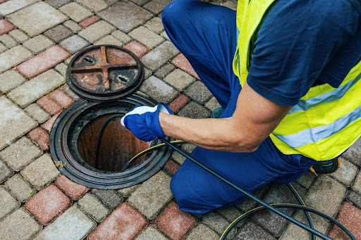 Professional technician inspecting drainage system with CCTV equipment near sewer manhole, emphasizing sewer cleaning services in London.